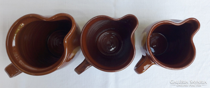Three brown-ochre striped ceramic jugs in a 