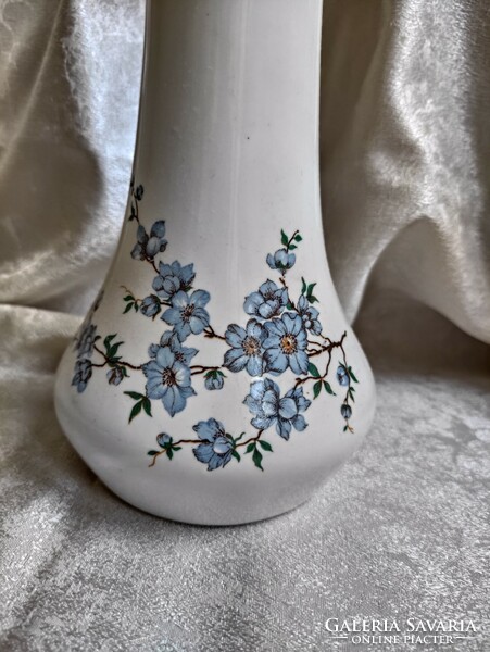 A tall aquincum porcelain vase with a long neck and a tree branch pattern with charming blue flowers