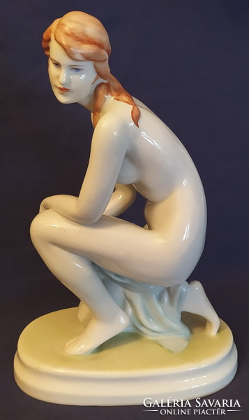 Statue of a female nude kneeling on an antique Zolnay pedestal