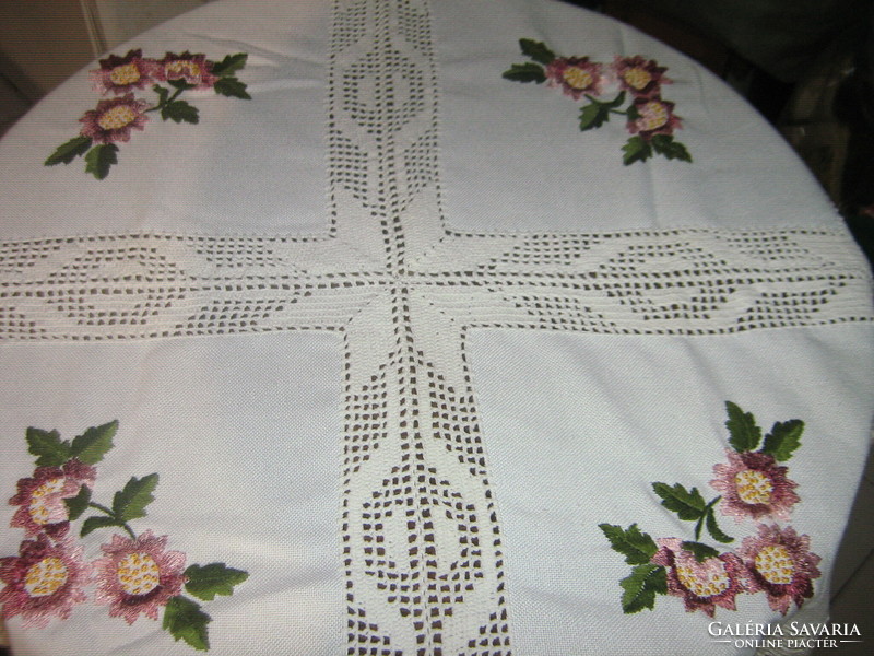 A beautiful hand-embroidered tablecloth with a hand-crocheted edge and a crocheted insert