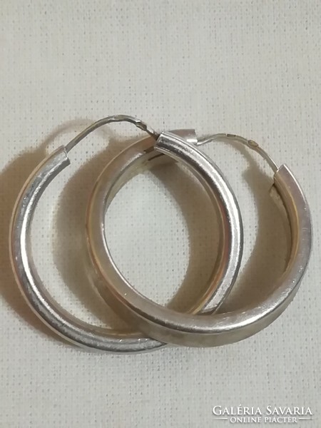Silver earrings with multiple markings.