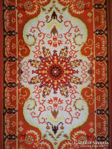 A small machine-made Persian carpet in an orange tone, a legacy of Inke László and Márta