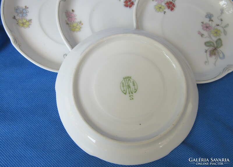 Older porcelain coffee set of 4 with a flower pattern, marked, slightly defective, one plate cracked.