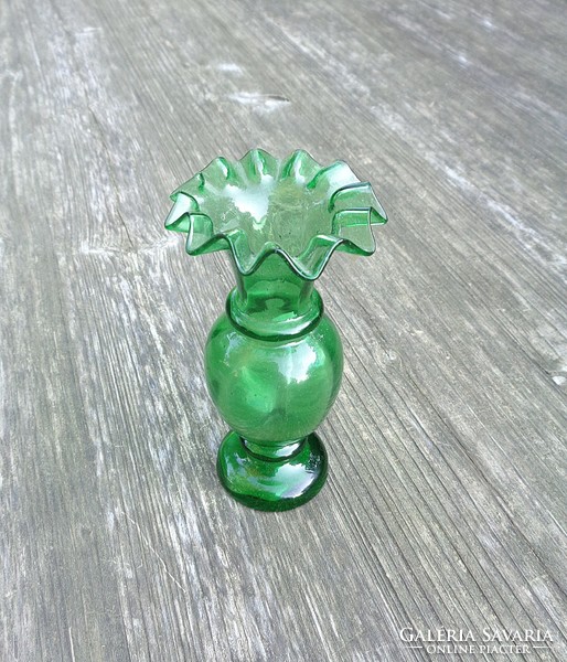Old green broken glass vase with ruffled edges