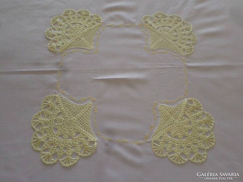A large snow-white tablecloth with pale yellow crocheted lace and embroidery on the edge.