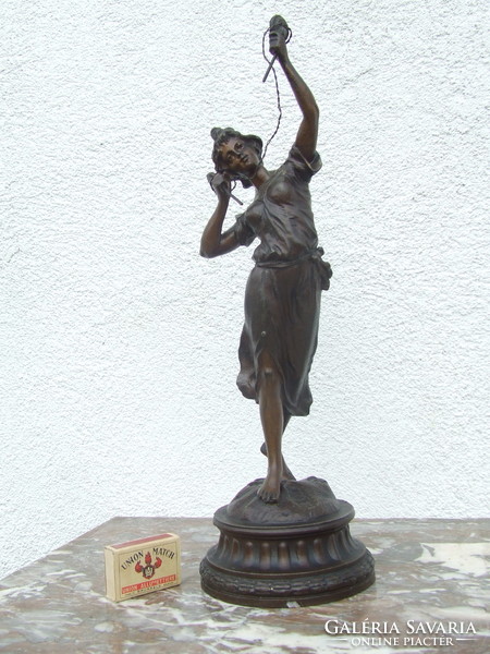 A spaiater statue of a woman examining electricity