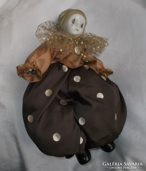 A clown doll with a porcelain head, hands and feet in puffy clothes