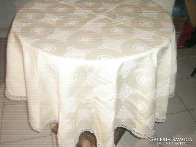 Beautiful elegant butter-colored round silk tablecloth with baroque pattern and lacy edges