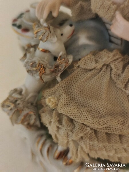 Old lacy baroque style porcelain figurine of a lady playing with a dog.