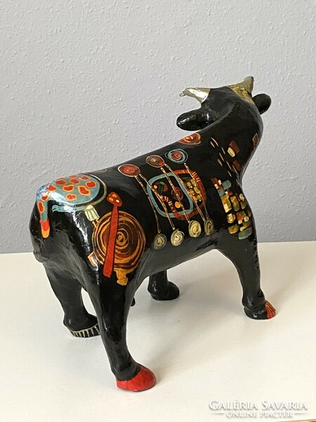 Paper mache cow sculpture with colorful modern abstract painting on a black background