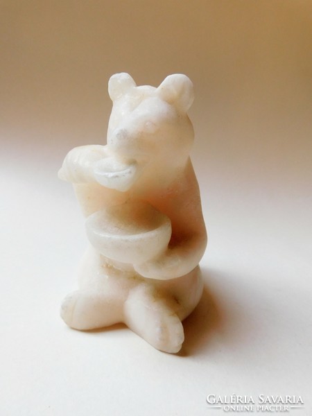 Stone carved bear figure scooping honey