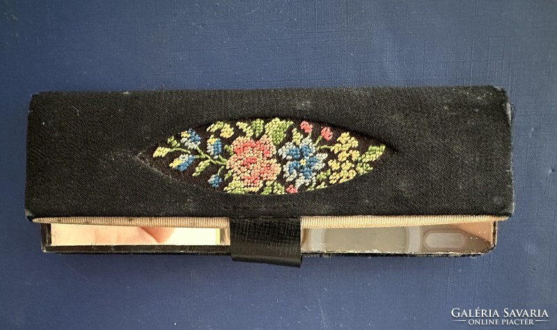 A small mirror in an embroidered holder