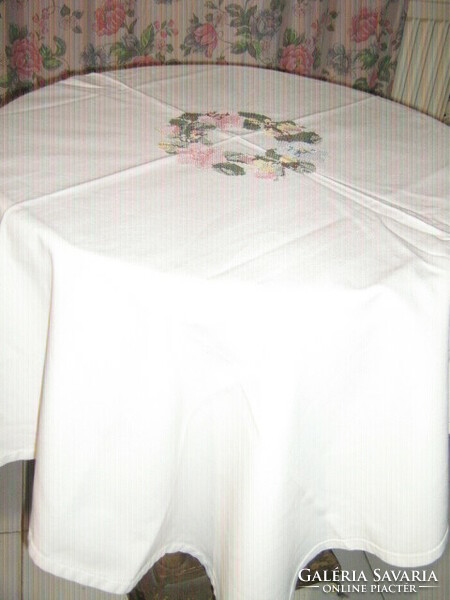 White woven tablecloth with beautiful cross-stitched wreath of flowers