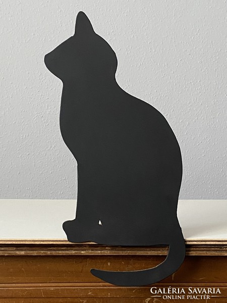 A cozy silhouette sculpture of a black cat sitting on a wooden board