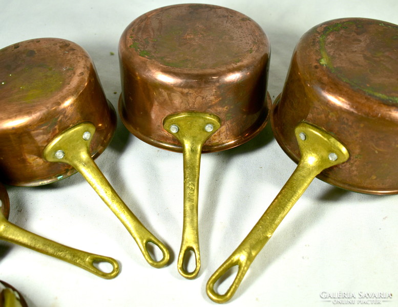 A set of small sauce-making pots with brass handles and red copper