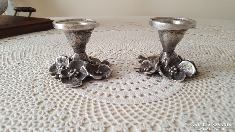 A pair of pewter candle holders decorated with old flowers