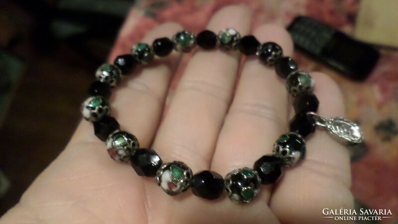 Bracelet strung on thin rubber, black glass or onyx and enamel beads with a small pendant.